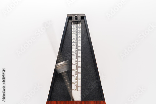 Old fashioned metronome with blurred arm indicating motion isolated on a white background