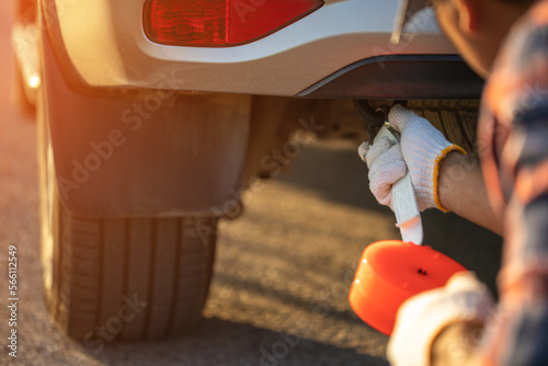 Man holding emergency car towing line and hook on backside of car on the roadside. Car accident, repair and maintenance concept