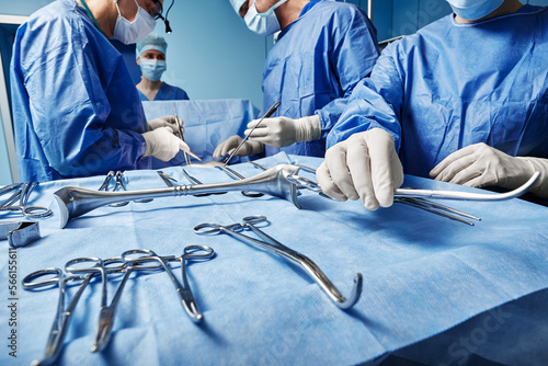 Surgical Team. Surgical nurse giving surgical scissors to male surgeon during operation in operating theatre
