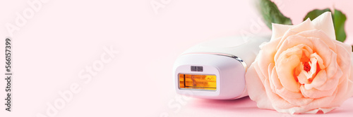 Home spa accessories - photoepilator on pink background. Apparatus and rose as a symbol. Banner. Copy space