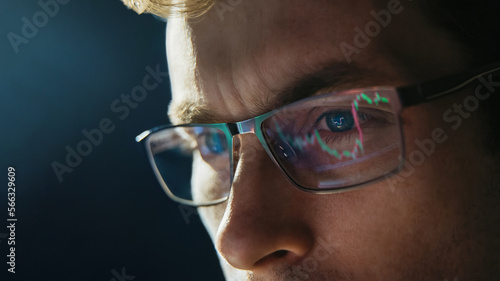 Portrait of trader wearing eyeglasses with reflection cryptocurrency chart. Close-up portrait of man analysing stock market. Copy space