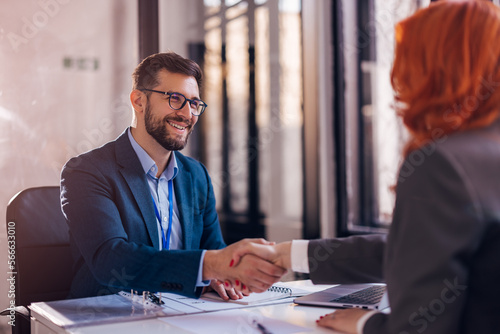 Happy bank manager shaking hands with a client after successful agreement in the office. 