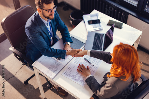 Happy bank manager shaking hands with a client after successful agreement in the office. 