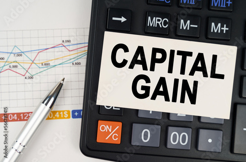 On the business chart lies a pen, a calculator and a business card with the inscription - capital gain