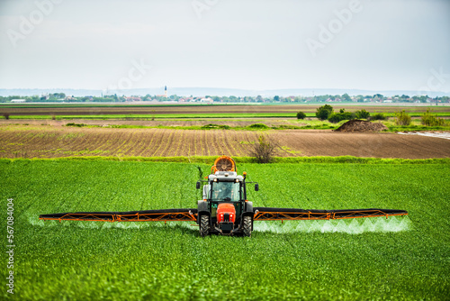 Herbicide, pesticide, and fungicide application in wheat fields with tractor, farmer protecting crops from pests and diseases