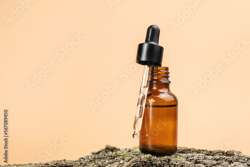 Open amber glass bottle with pipette on natural wood on beige background. The concept of natural, organic cosmetics. Side view, space for text.