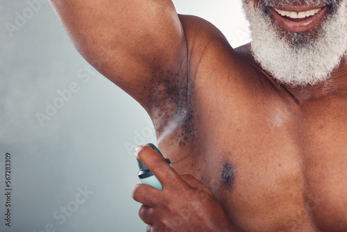 Old man, spray armpit with skin and smile for beauty, grooming and hygiene isolated on studio background. Happiness, wellness and skincare, cosmetic product and topless with deodorant and fragrance