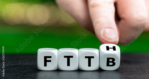 Hand turns dice and changes the expression Fiber to the building (FTTB) to Fiber to the home (FTTH). Symbol for connecting residences directly with optical fibers.