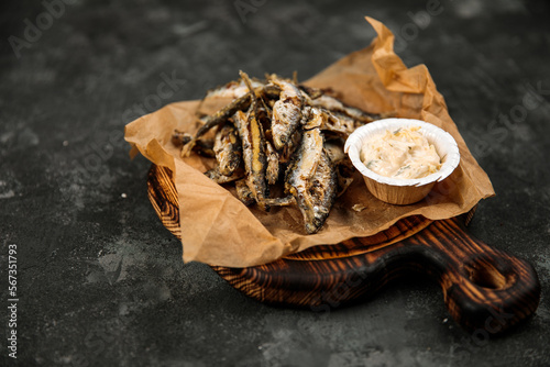 fried vendace with sauce, national Karelian dish northern Russian cuisine on a wooden tray, on a dark background
