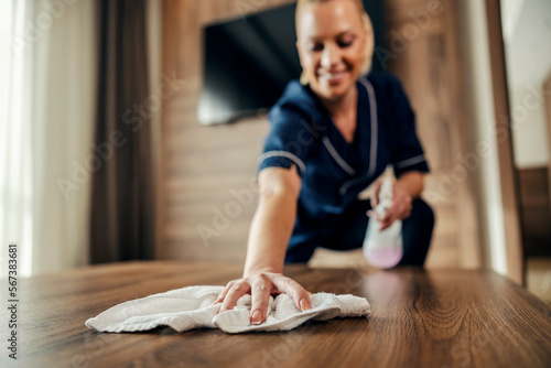 Close up of a maid cleaning floor with cloth and detergent in a hotel room.