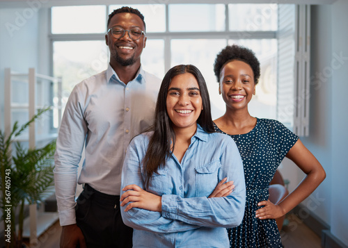 Group of smiling business people pose arms folded in office, diverse trio