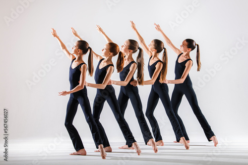 Group of children, little girls in sportive style clothes dancing in choreography class isolated on background