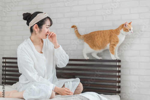 ベッドルームにいる猫アレルギー・匂いが苦手な女性と猫 