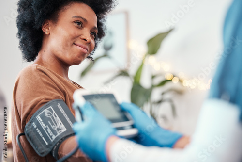 Black woman, healthcare and blood pressure machine in checkup with caregiver for monitoring pulse at home. Happy African American female patient or visit from medical nurse for health and wellness