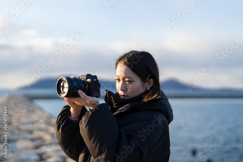 夕暮れの海で写真を撮る女性