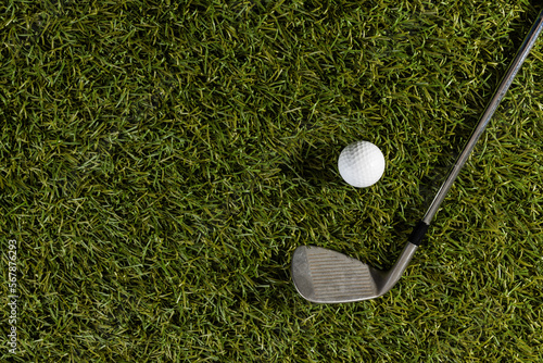 High angle view of white golf ball and golf club on grass with copy space