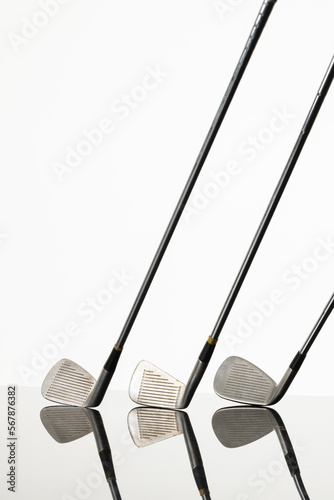 Close up of three golf clubs with copy space and reflection on white background