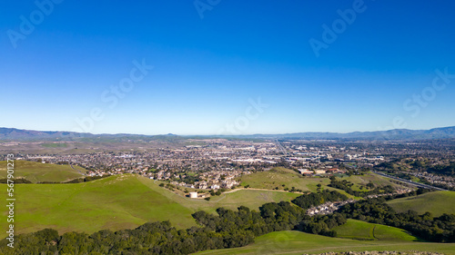 Aerial photos over the Dublin Hills in Dublin, California with a city in the background with a blue sky