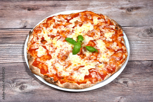 Pizza margherita with tomato mozzarella and basil in a plate isolated on wooden background