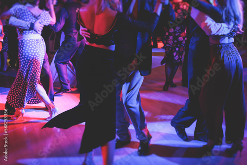 Couples dancing traditional latin argentinian dance milonga in the ballroom on a festival, tango studio, salsa, bachata and kizomba lesson in the red and purple lights, rehearsal in the dance class