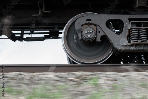 Wheels and bogie of freight train moving fast along railroad.