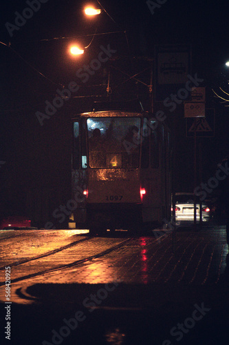 a tram is filled with passengers during a heavy snowfall at night in the city on a cobbled street