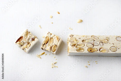 Torrone - torrone morbido italiano con mandorle isolate su sfondo bianco. Stagione delle vacanze. Copia spazio.