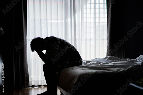 Lonely man silhouette feeling depressed and stressed sitting head in hands in the dark bedroom, Depression and anxiety disorder concept