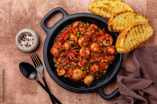Italian stew cuttlefish with green peas and tomatoes or seppie con piselli in umido. Toasted bread.