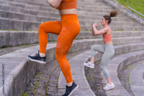 Two young fitness girls in a city park, working out their legs on the stairs
