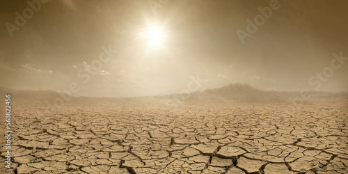 Barren terrain panorama, sun shining over cracked dried land and clouds of dust. Climate change concept