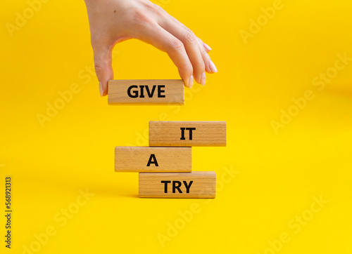 Give it a try symbol. Concept words Give it a try on wooden blocks. Beautiful yellow background. Businessman hand. Business and Give it a try concept. Copy space.