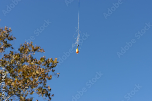 Orange float with a fishing line dangling on the blue sky background