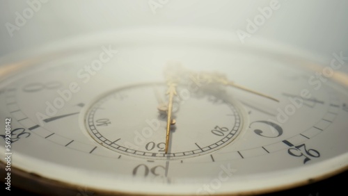 Antique pocket watch with a white dial and gold hands in bright light. The face of an old clock with numbers extra close up. Round mechanical vintage pocket watch.