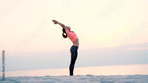 Healthy, young beautiful woman meditating, practicing yoga among the sand, on the beach, by the sea, river, at dawn, at sunrise, closeup
