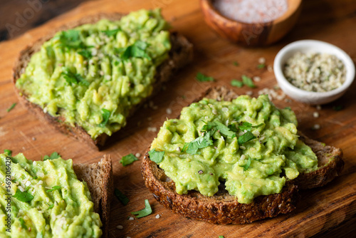 Vegan avocado toast with cilantro and hemp seeds on a wooden background, closeup view. Healthy snack