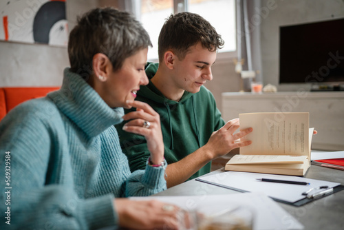 One student teenage caucasian man study learn with help of his tutor professor or mother senior woman at home having private lesson to prepare for exam education concept real people copy space