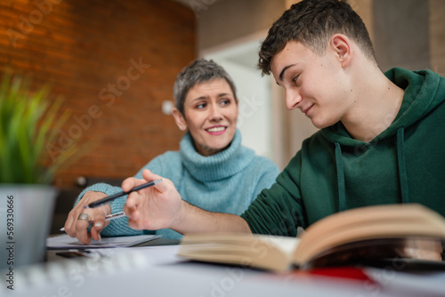 One student teenage caucasian man study learn with help of his tutor professor or mother senior woman at home having private lesson to prepare for exam education concept real people copy space