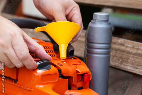 Unscrewing the cap of the fuel tank of the chainsaw for refueling a mixture of gasoline with 2-stroke oil.