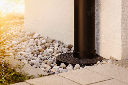 French Drain Stone Pebble and Waterspout. Downspout with Drainage Floor Gravel outside House