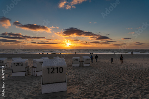 A group of beach chairs with tourists and the beach view into the sunset, Baltic Sea, Sylt, Germany.