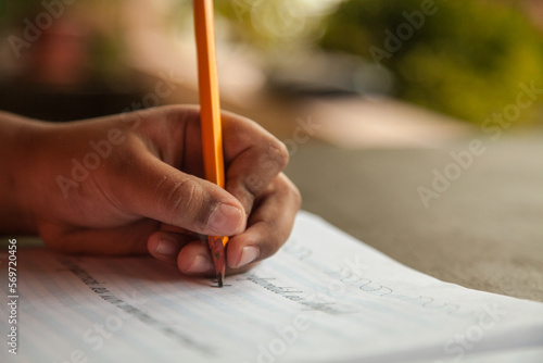 Escribiendo con lápiz amarillo en cuaderno pautado