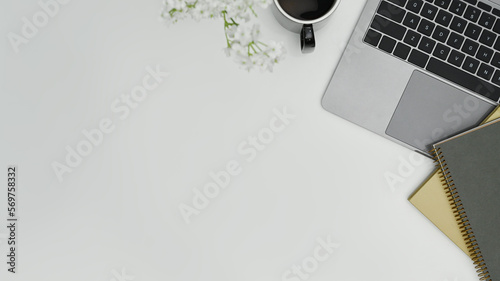 White office desk with laptop computer, books and flowers. Top view with copy space for text