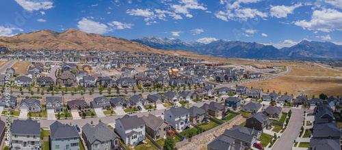 Aerial view of houses in Lehi Utah with mountains and blue sky background. Residential neighborhood landscape in an affluent area known as Silicon Slopes.