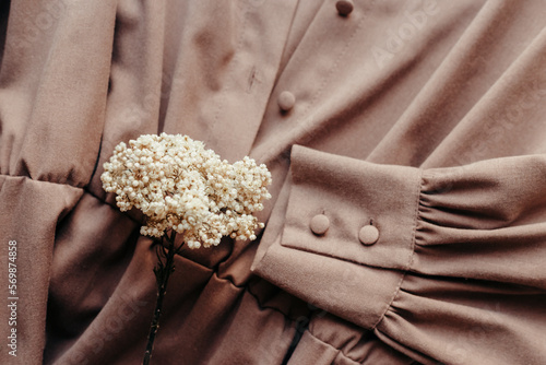 Brown women dress with collar and buttons and dried flowers. Women's stylish autumn or summer outfit