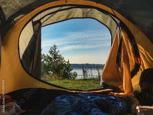 View from the tent to the river. Hiking concept. Dawn in a tent. No people. Tourists. Orange awning.