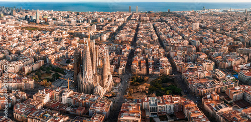 Aerial view of Barcelona City Skyline and Sagrada Familia Cathedral at sunset. Eixample residential famous urban grid. Cityscape with typical urban octagon blocks