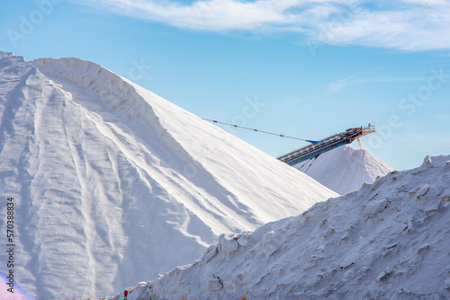 Aigues-Mortes Saltworks, pile of salt with machinery industrial scenery of salt mine. A mountain of salt in the marshes in France, Europe, summer