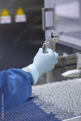 a hand in a medical latex glove holds a glass ampoule for vaccines. Medical glass vials. Close-up. Quality control