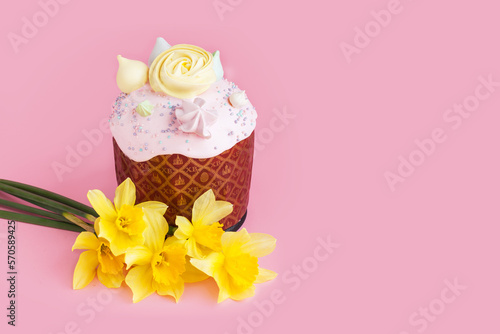 Traditional russian Easter ortodox cake with daffodil flower and colorful eggs on light pink background. Kulic, Kulich, Paska homemade bread with glaze. Spring christian holiday. Festive celebration